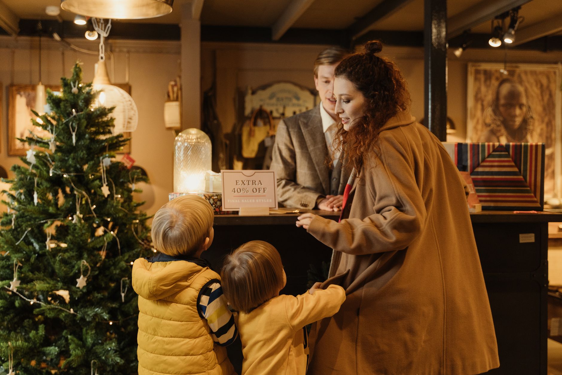Family enjoying holiday shopping at a decorated store with a Christmas tree and sale offer.