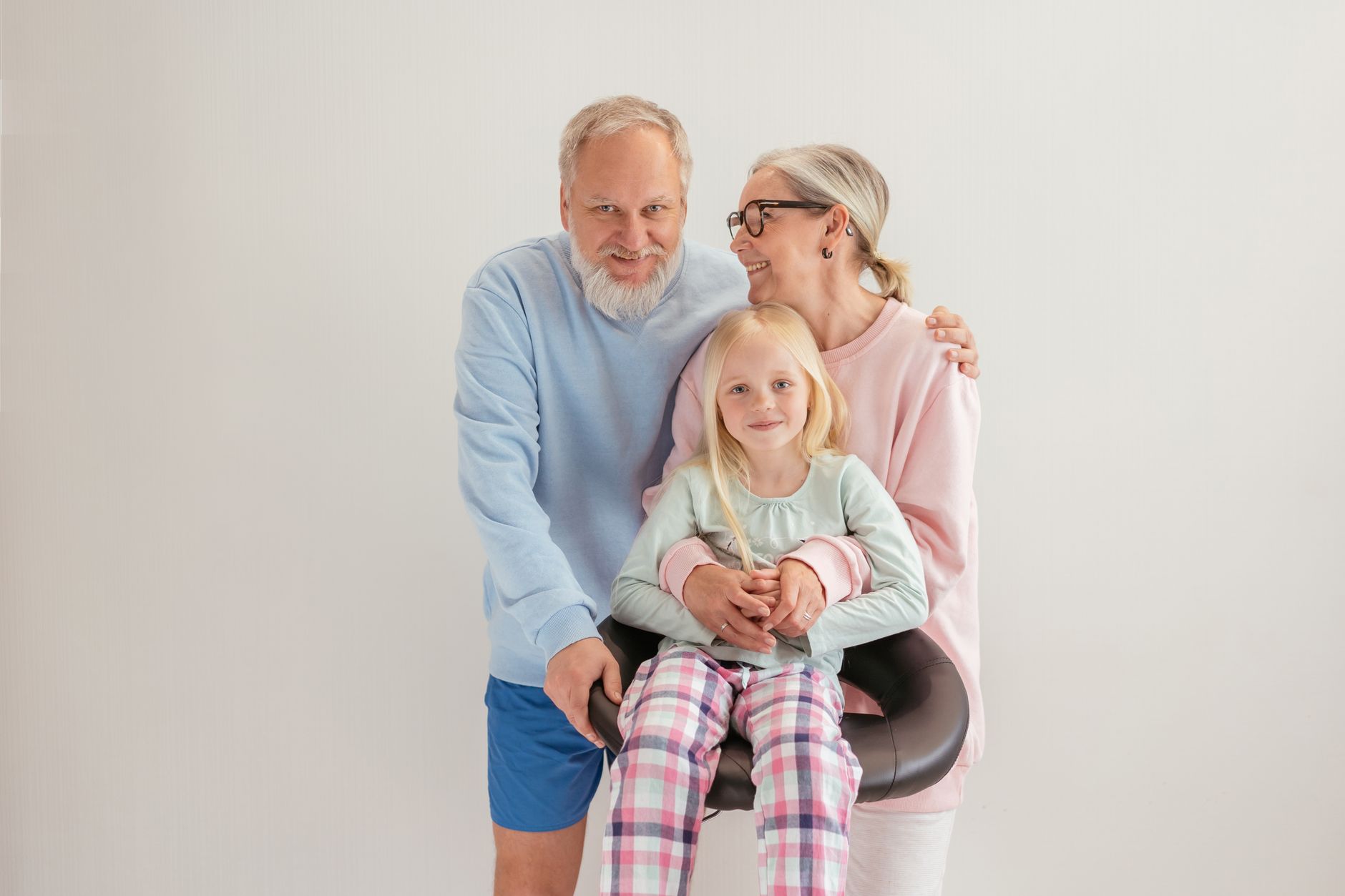 Smiling grandparents with grandchild, embracing intergenerational love.