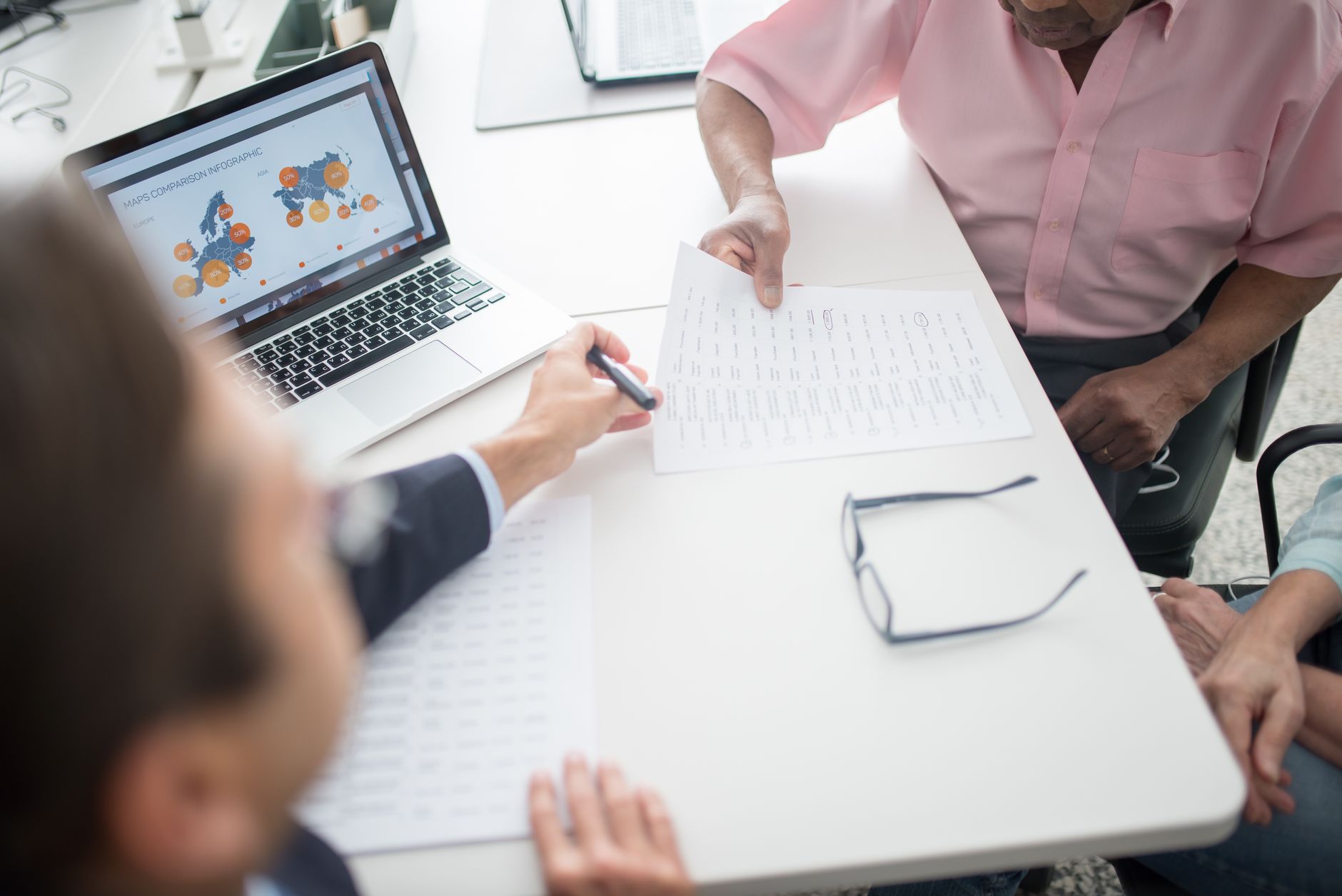 Senior couple reviewing documents with consultant at office desk with laptop.