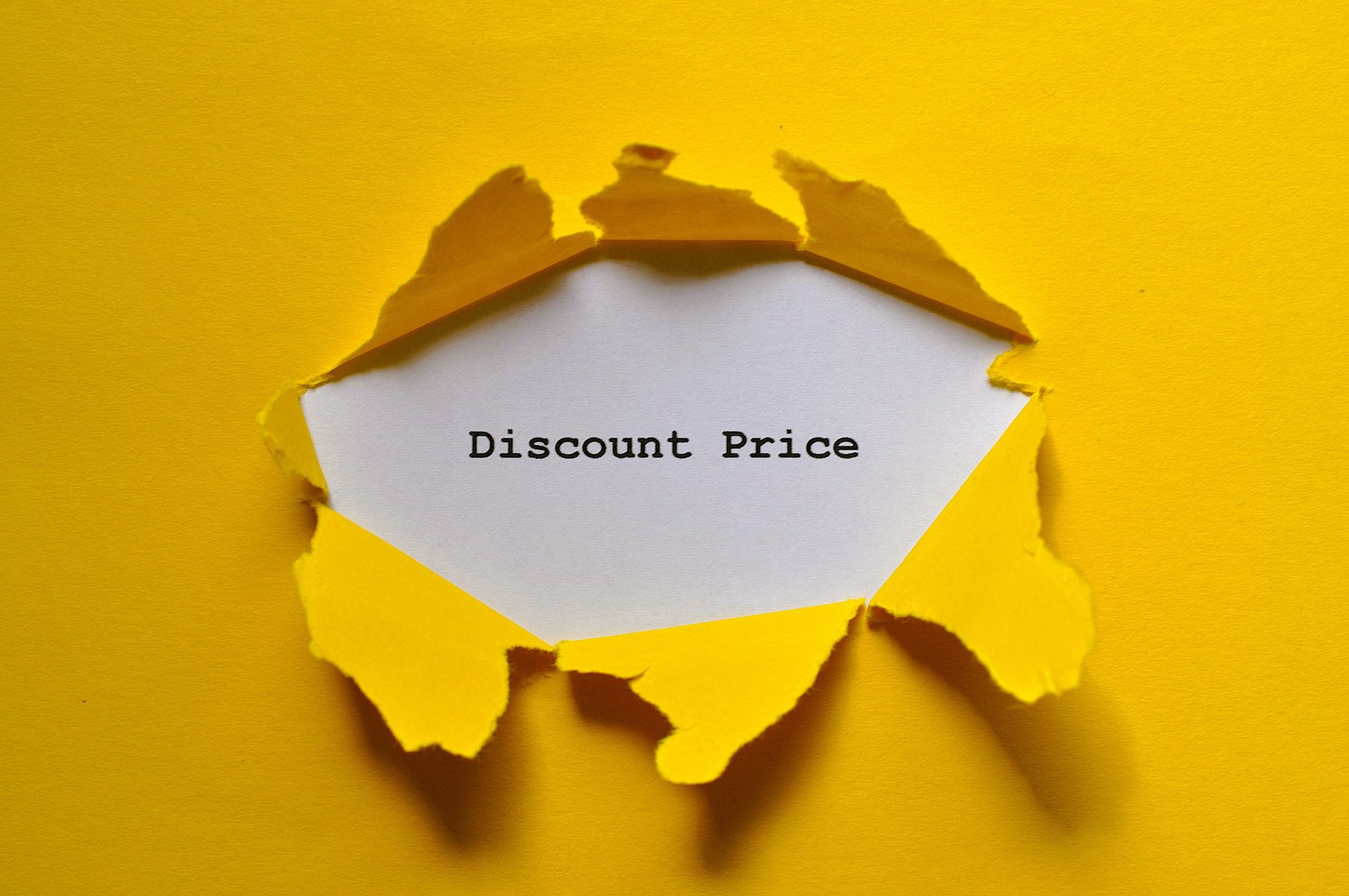 Torn yellow paper revealing 'Discount Price' text, ideal for sales promotions.