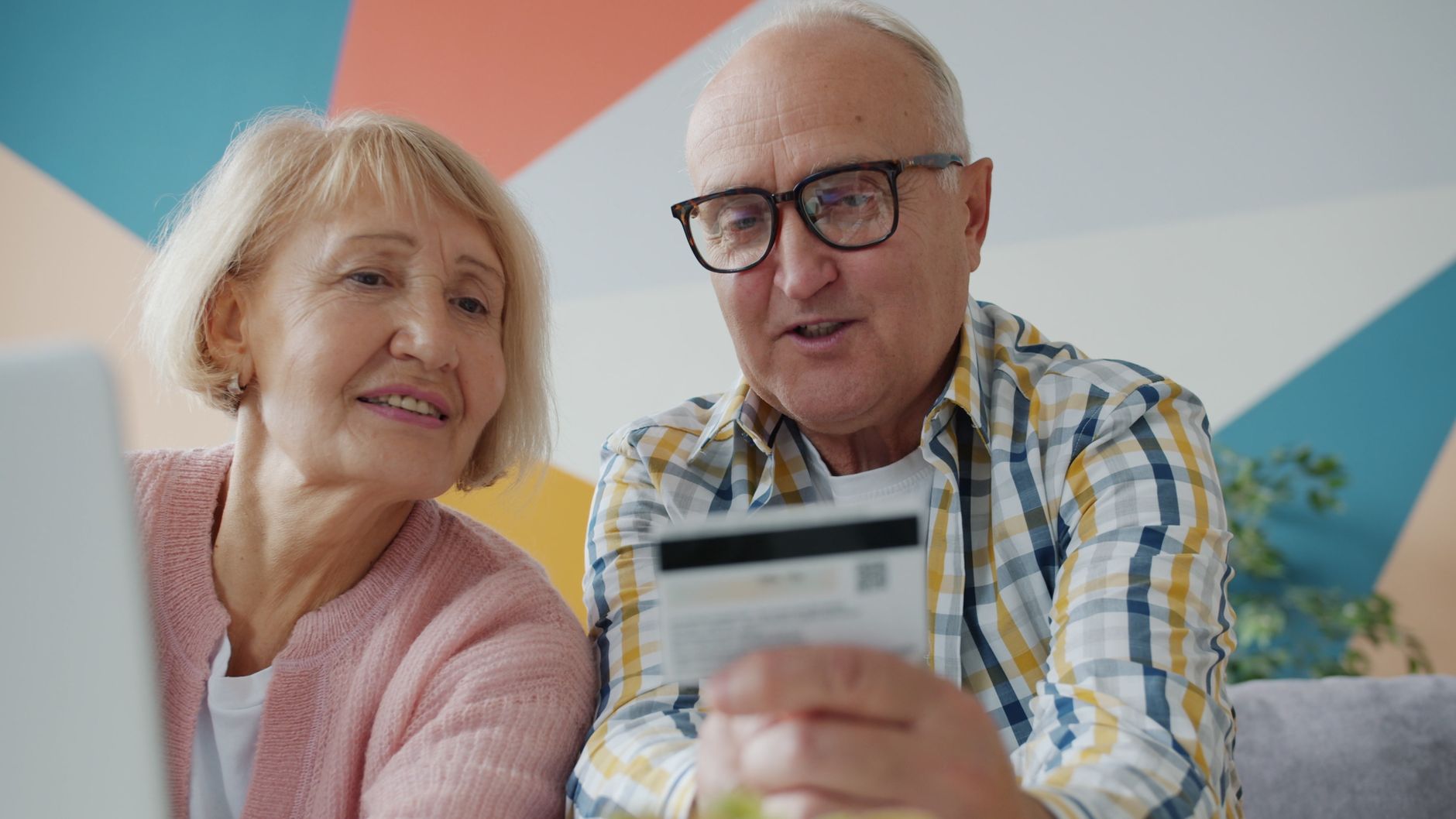 Senior couple using a credit card while shopping online at home.