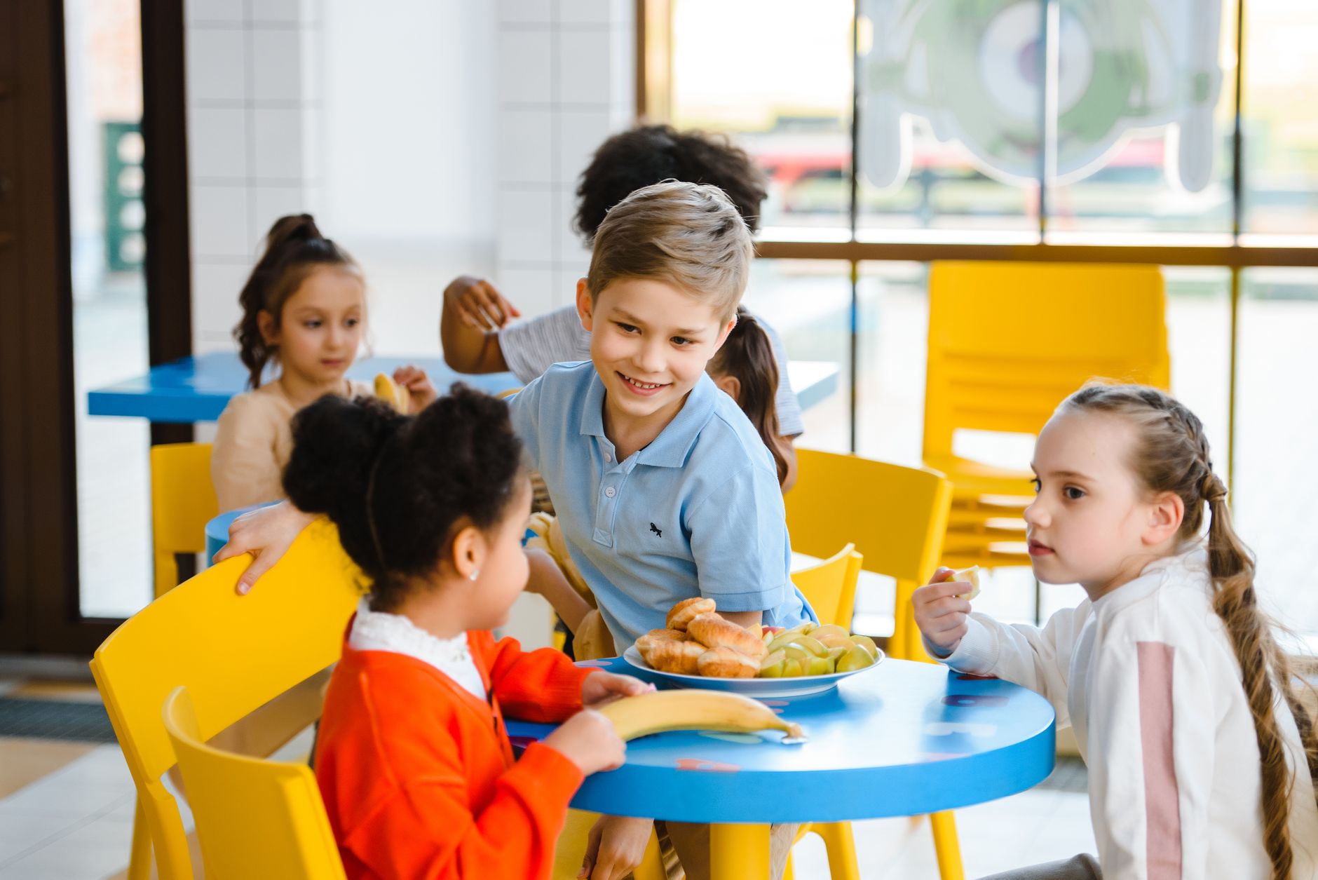 Group of cheerful kids enjoying lunch together in a bright school cafeteria.
