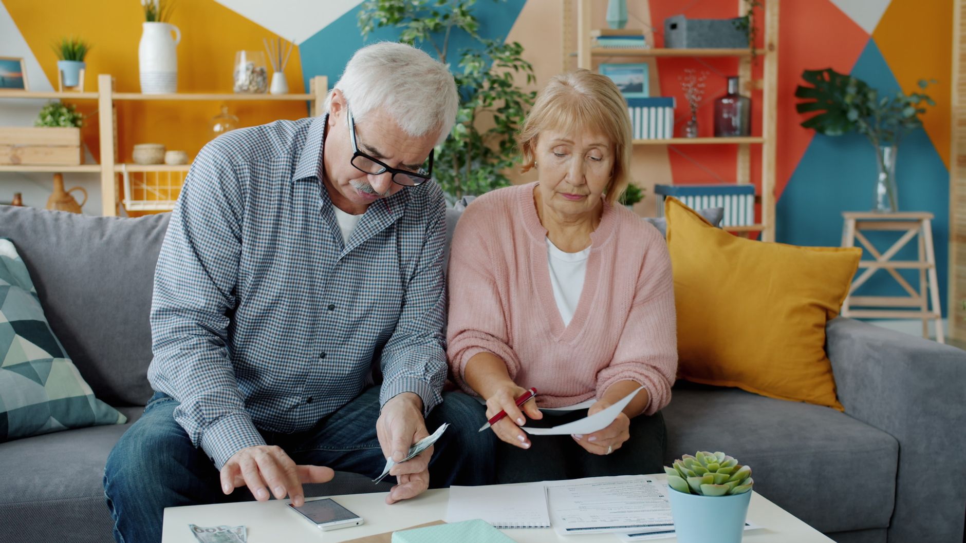 Elderly couple organizing their finances on a cozy living room couch.