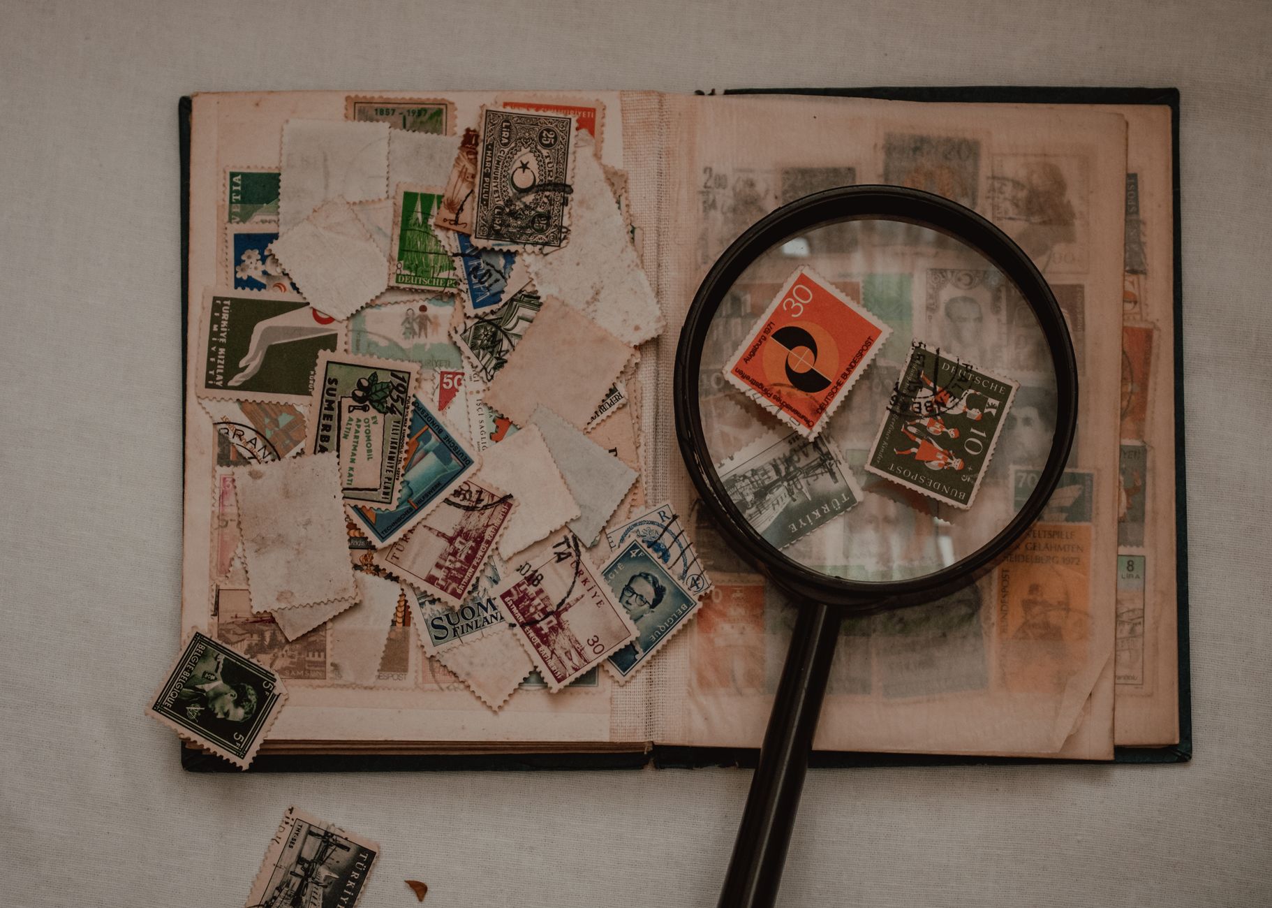 Flatlay of an antique stamp album with a magnifying glass. Perfect for collectors.