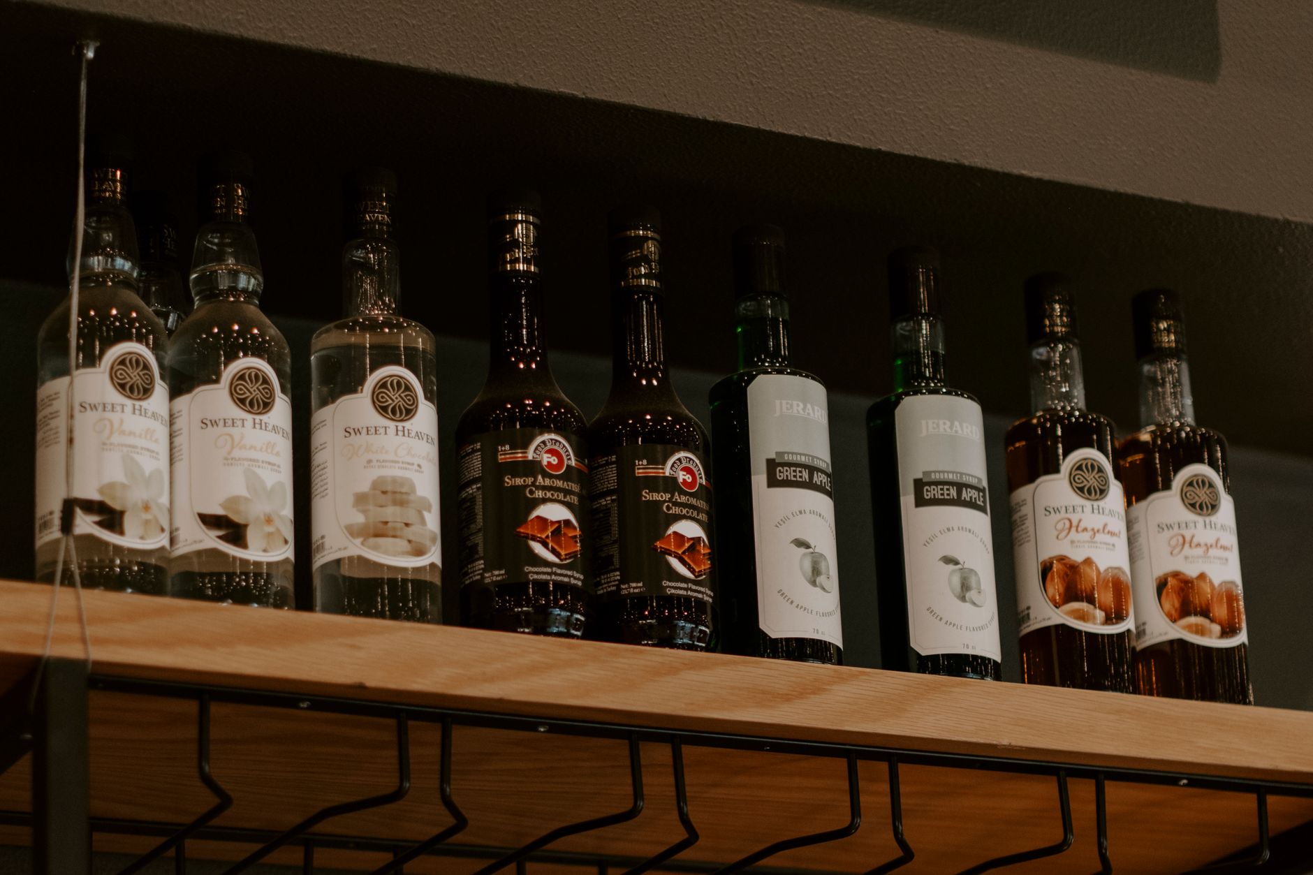 Assorted bottles of alcohol neatly arranged on a wooden shelf in a liquor store.